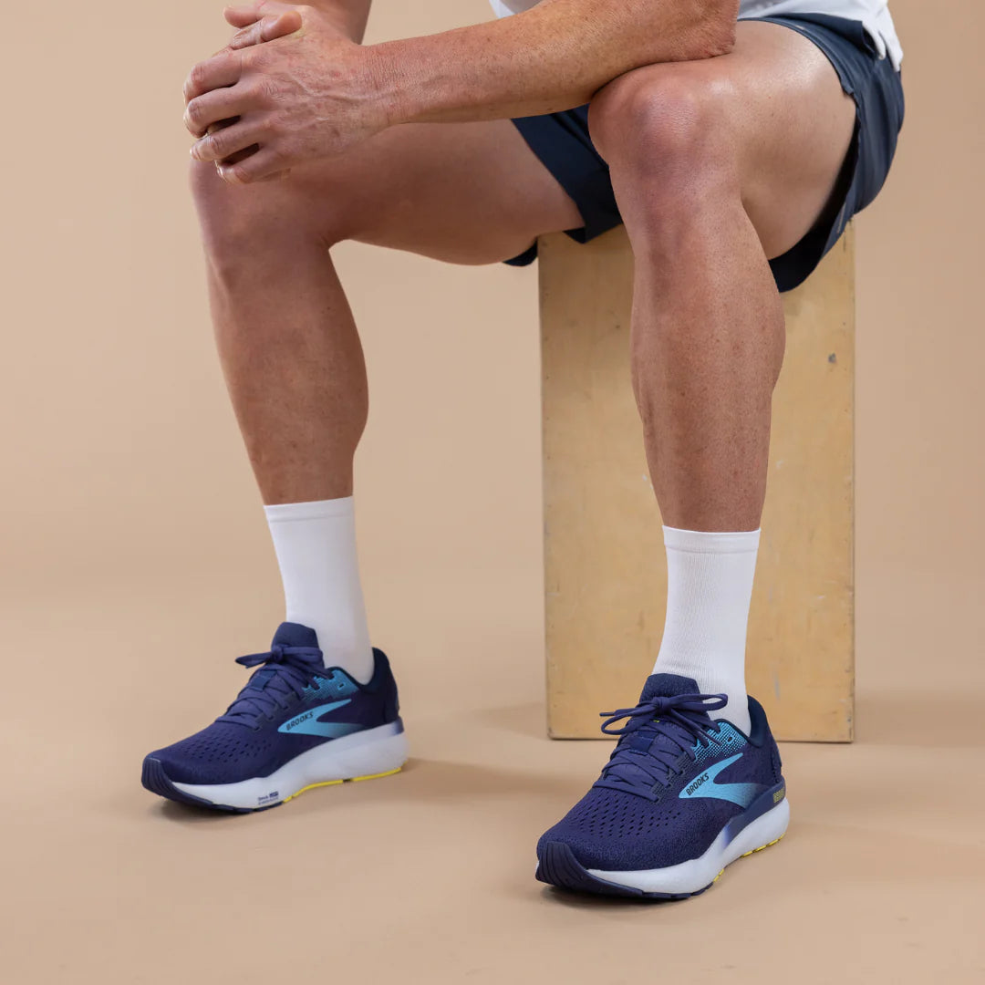 Person wearing blue running shoes with white Lightfeet socks on a beige background