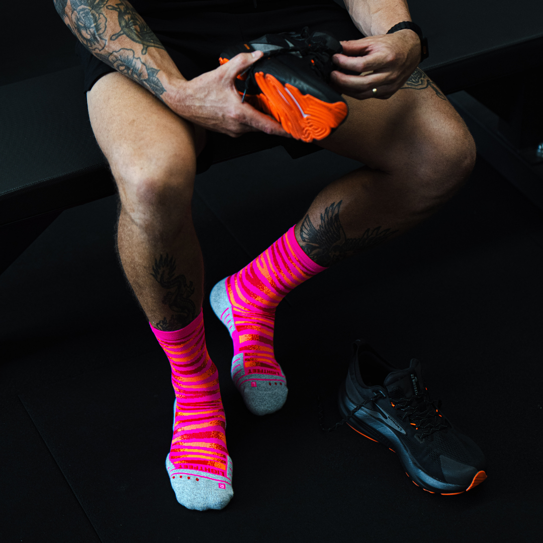 Image of person wearing Lightfeet Performance Predator Pink Red Orange Half Crew Socks 