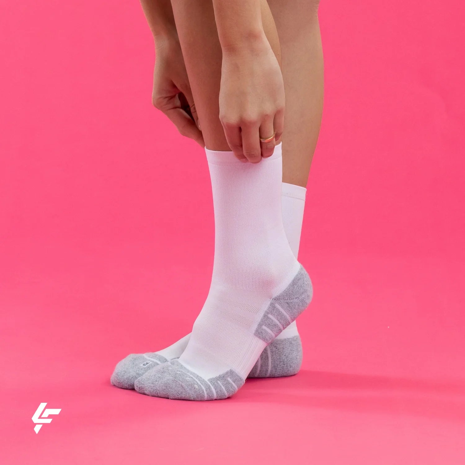 White Lightfeet socks with gray toes and heels on a pink background